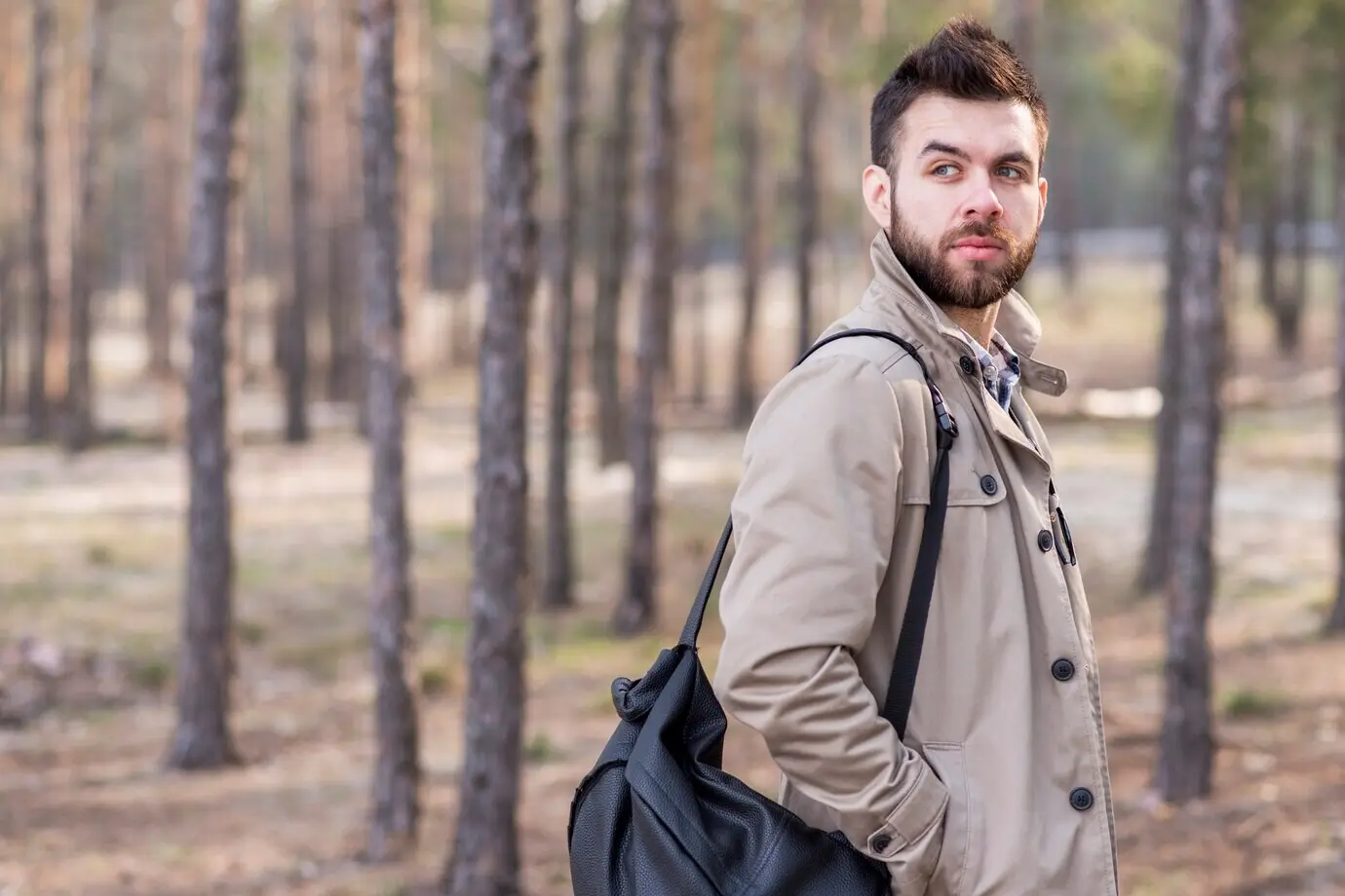 Ein gutaussehender männlicher Reisender mit einem Rucksack auf der Schulter, der wegschaut.